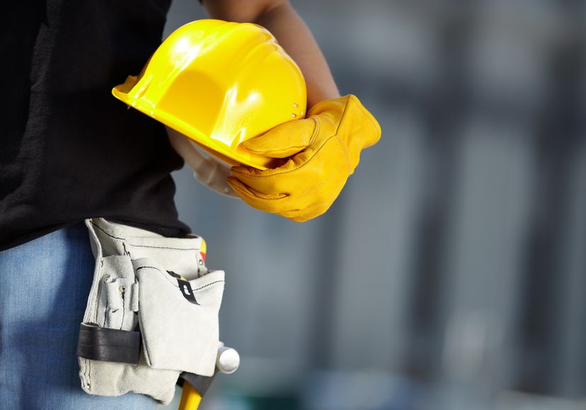 Gloved worker holding a hard hat