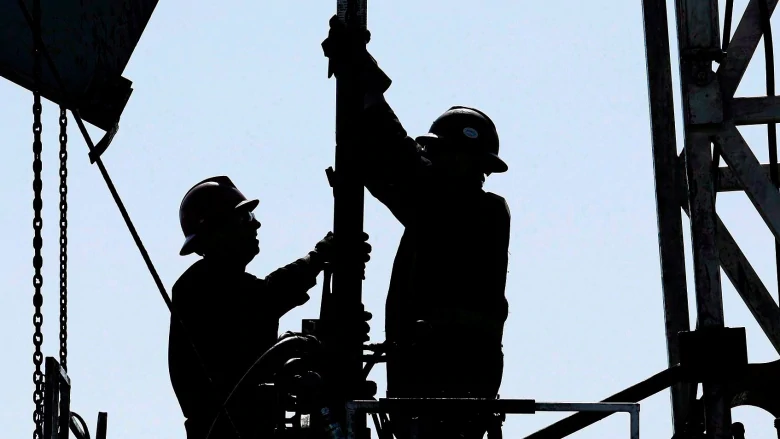 Workers silhouetted on a drilling rig