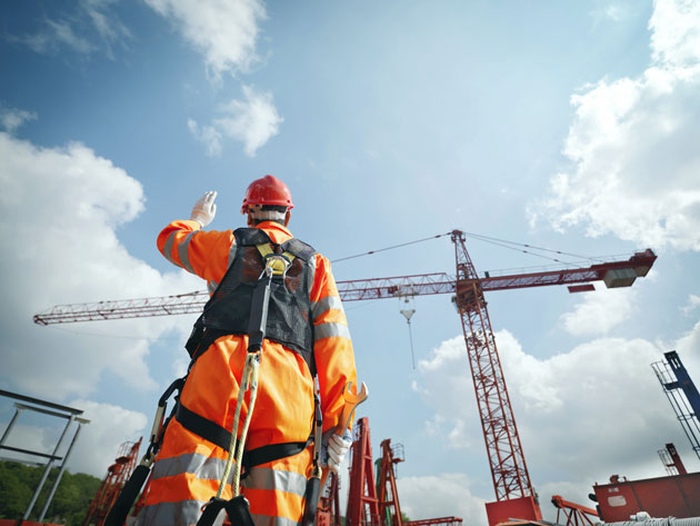 Rig worker in harness signalling a crane
