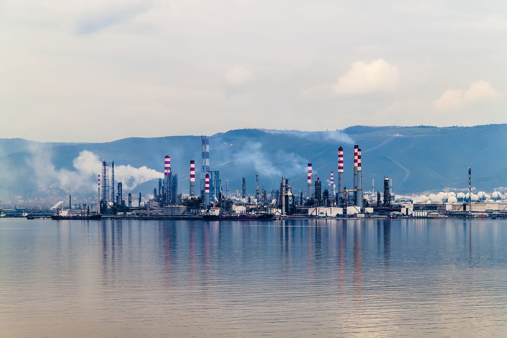 Coastal refinery reflected in calm water